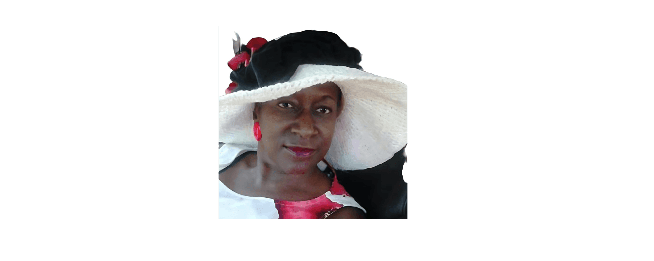 Woman wearing a large white sun hat with black and red accents, and red earrings.