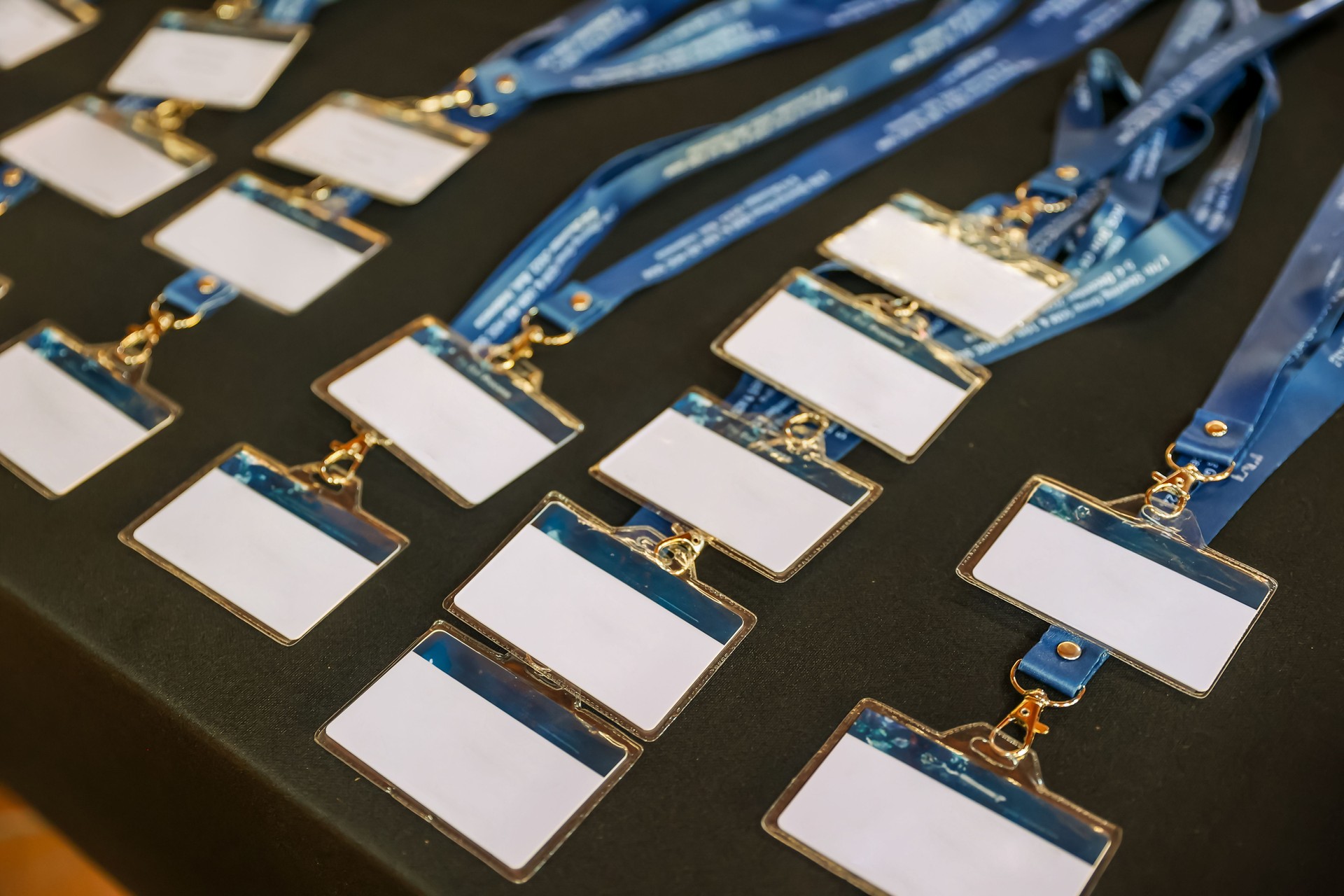 Many plastic badges on the table. Blank ID cards with blue lanyard ribbons for conference, business meeting, training course, lectures, seminars, show, concerts or other events